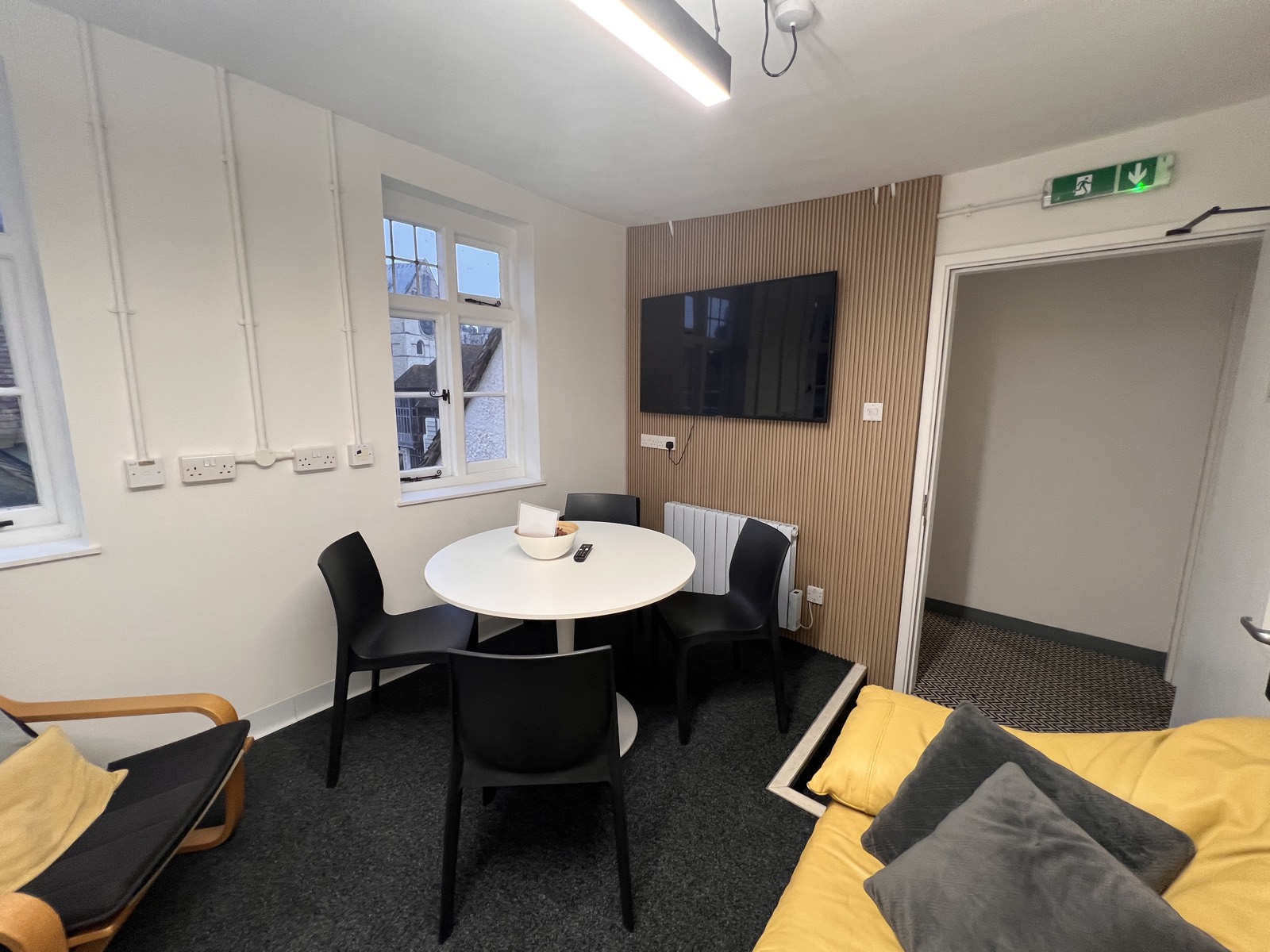 The Chapter House — the round meeting table, oak-slat wall and the Cathedral Quarter rooftops through the window